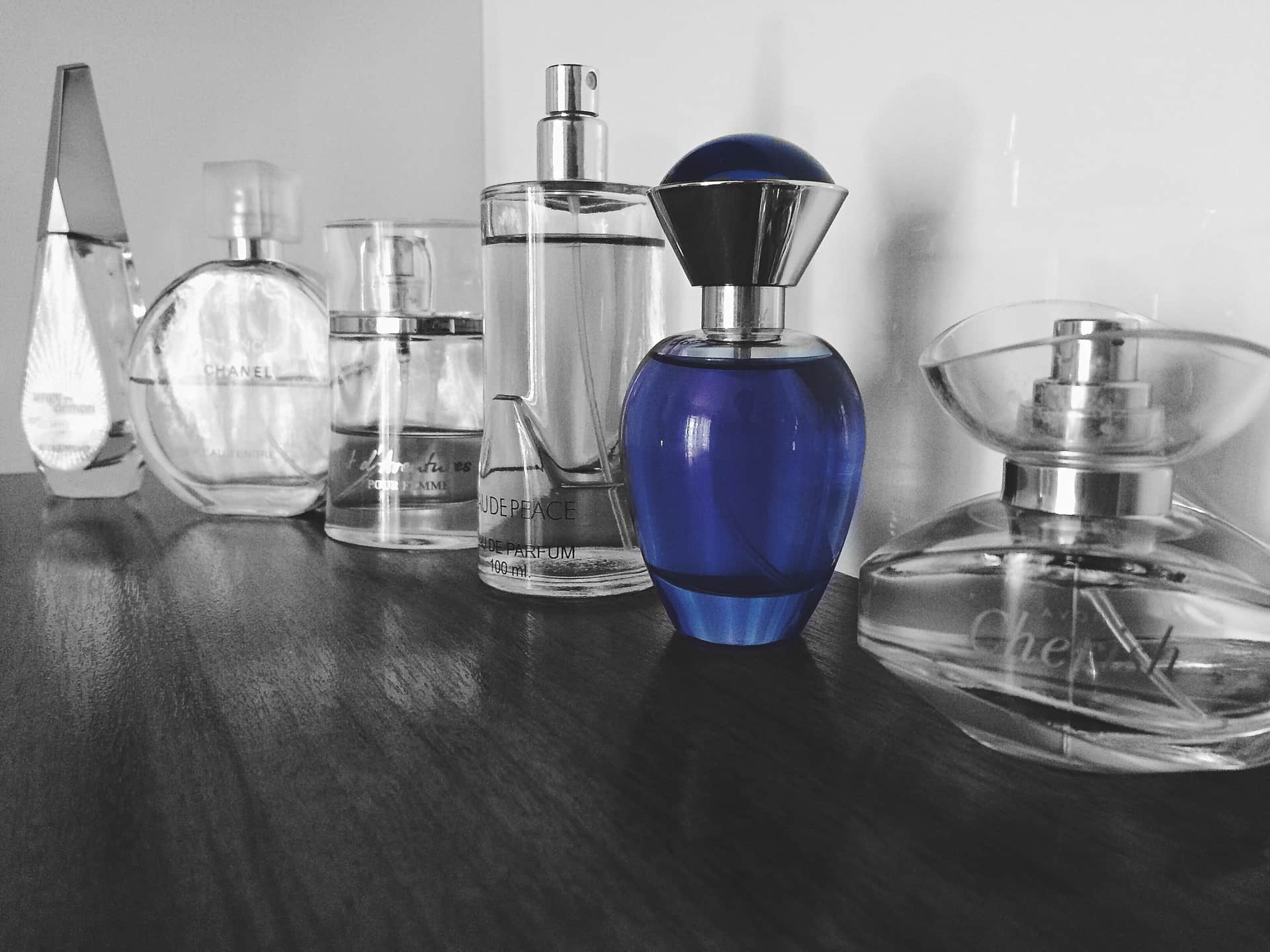 A row of cologne bottles on a warm wooden shelf in soft natural light