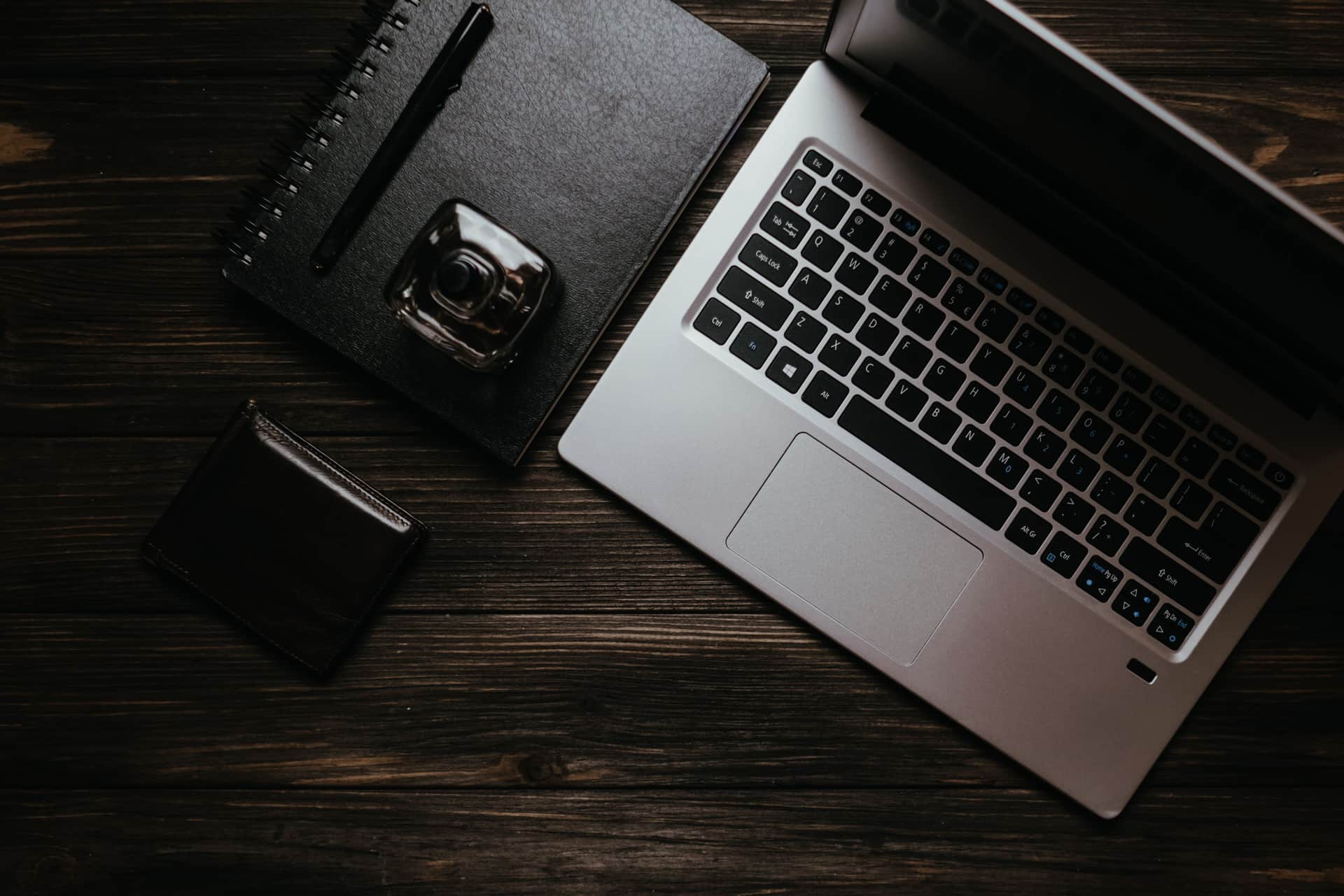 A cologne bottle beside an open notebook on a warm wooden desk