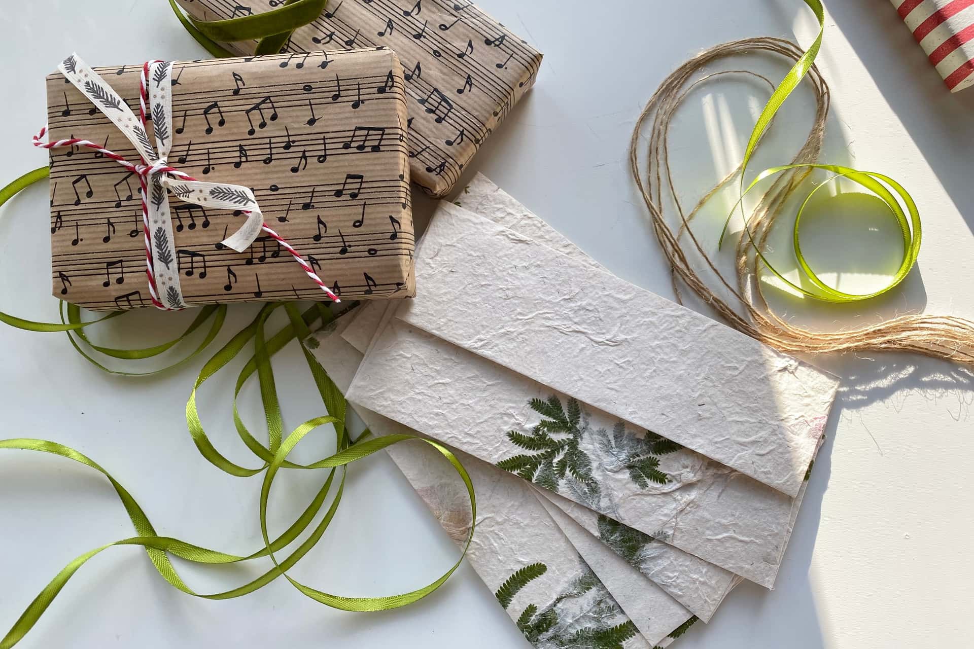 Gifts wrapped in kraft paper with twine and green ribbon on a sunlit table